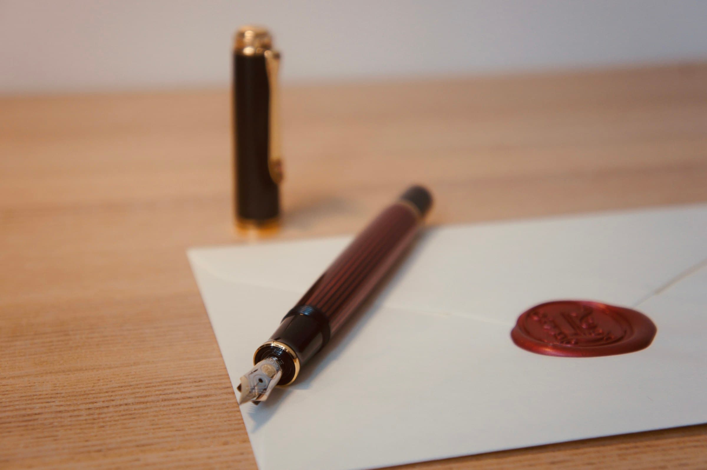 Fountain pen beside a wax-sealed envelope on warm timber: the formal court correspondence behind an intervention order